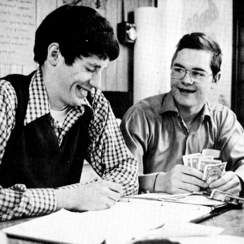 Financial staff members Doug Hultberg and Dan Mundt laugh over a mistake in the account book