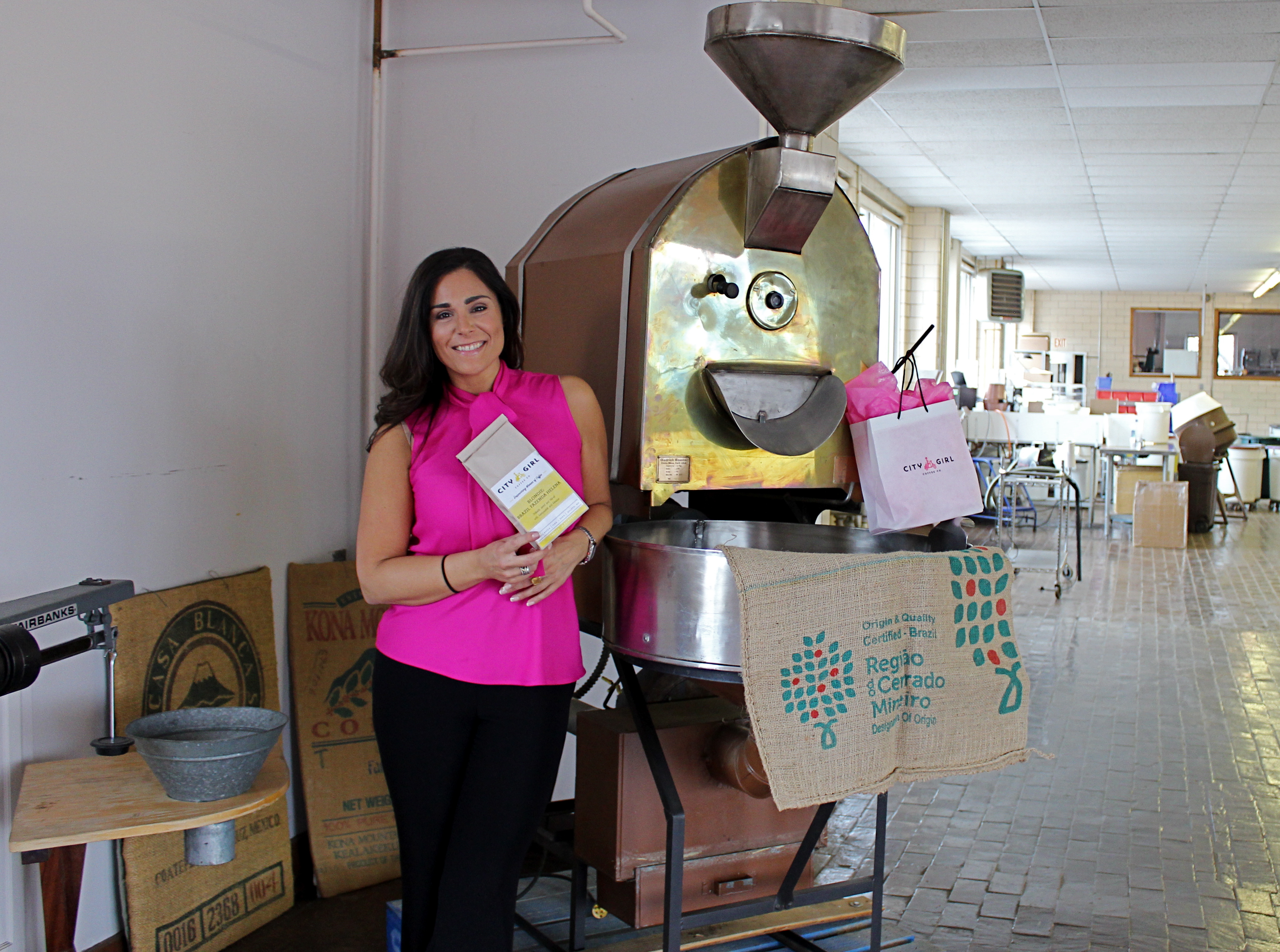 Alyza Bohbot poses in front of Alakef's original roaster with City Girl Coffee swag