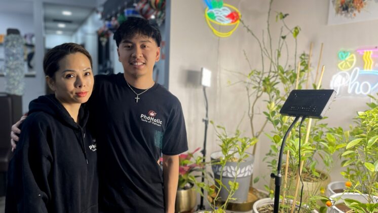 Ann and Alijah Nguyen standing inside the restaurant with plants and neon lights